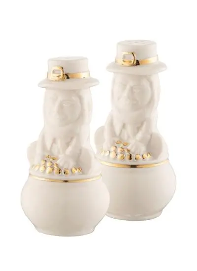 Two ceramic salt and pepper shakers designed to look like leprechauns wearing white hats and green shamrock belts, isolated on a white background.